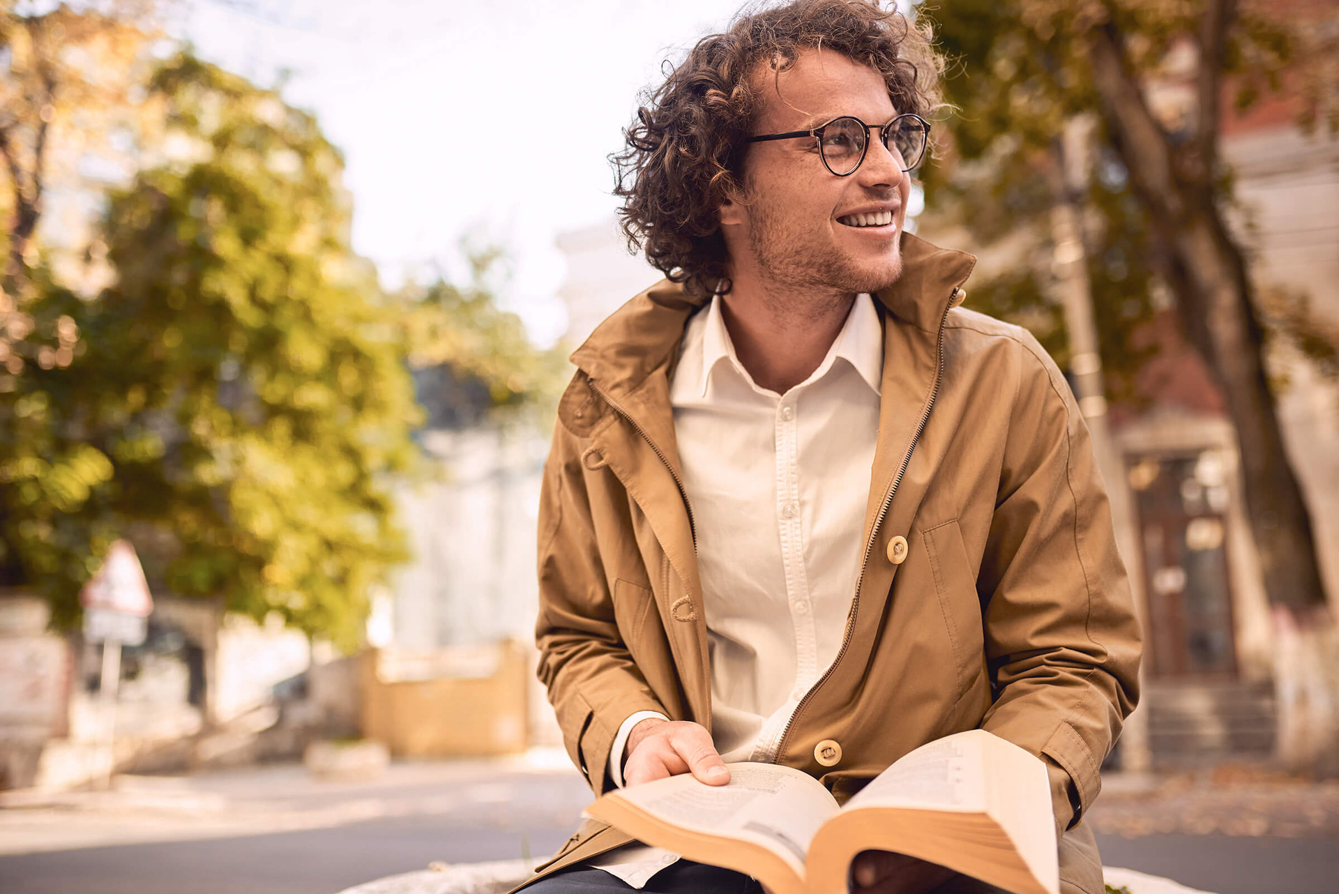 Ein Mann sitzt auf einer Straße und liest ein Buch.